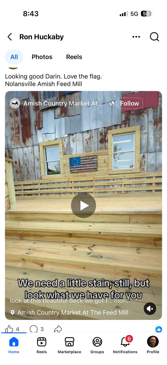 Reclaimed barnwood American flag displayed on deck railing at Amish Country Market, Feed Mill building in background