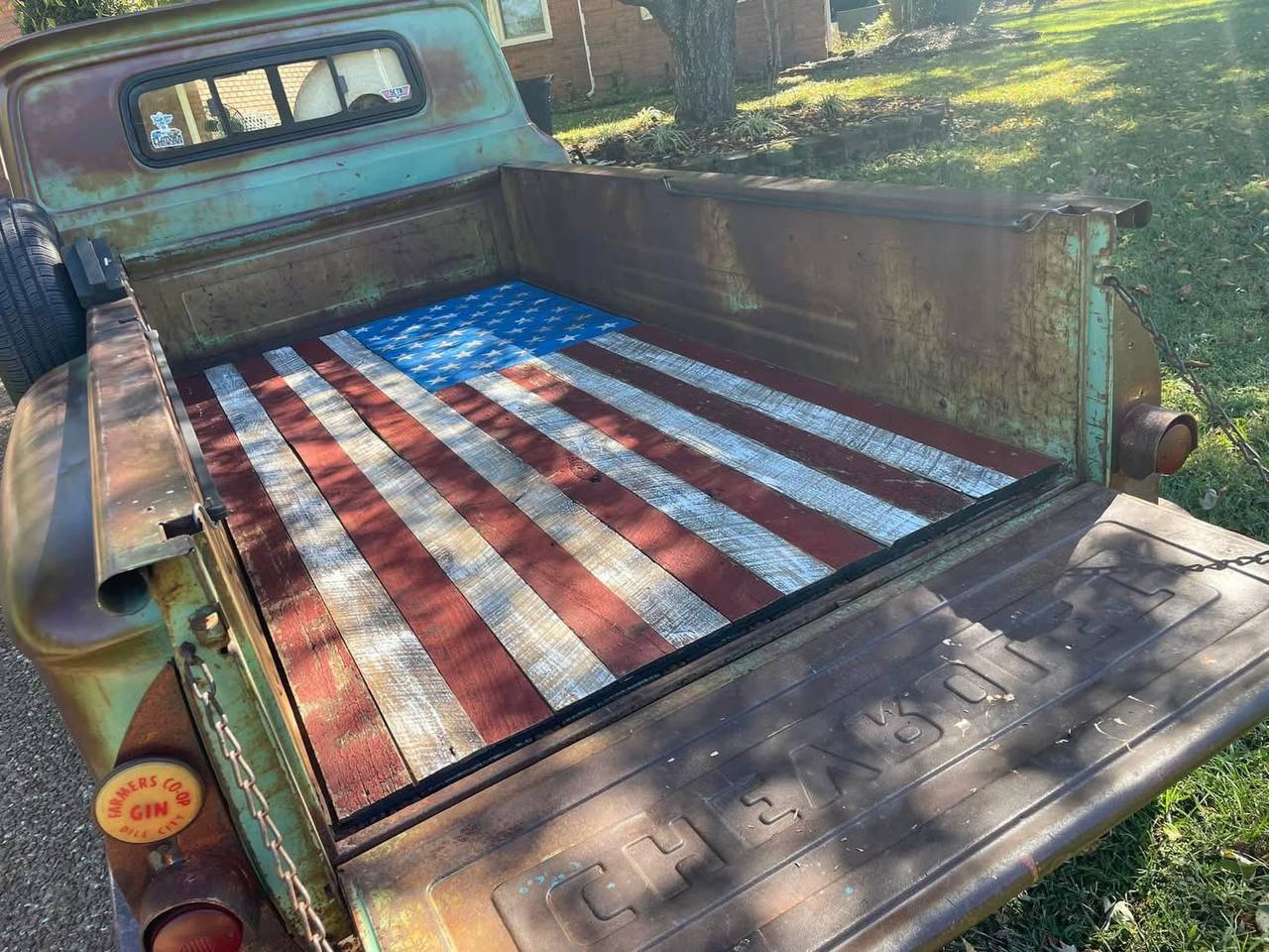 Barnwood American flag as a custom truck bed floor in a vintage green Chevy — Farmers Coop Gin sticker visible